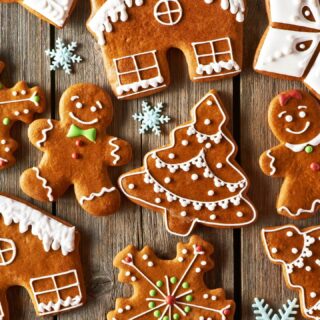Gingerbread cookies in person, house, evergreen tree and snowflake shapes decorated with white icing